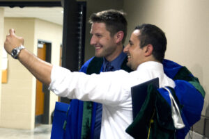 Two male LECOM graduates taking a selfie after LECOM graduation ceremony.